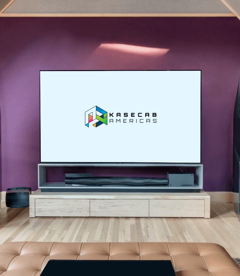 A television displaying the Kasecab Americas logo sits on a light wood TV stand against a purple wall in a modern living room.